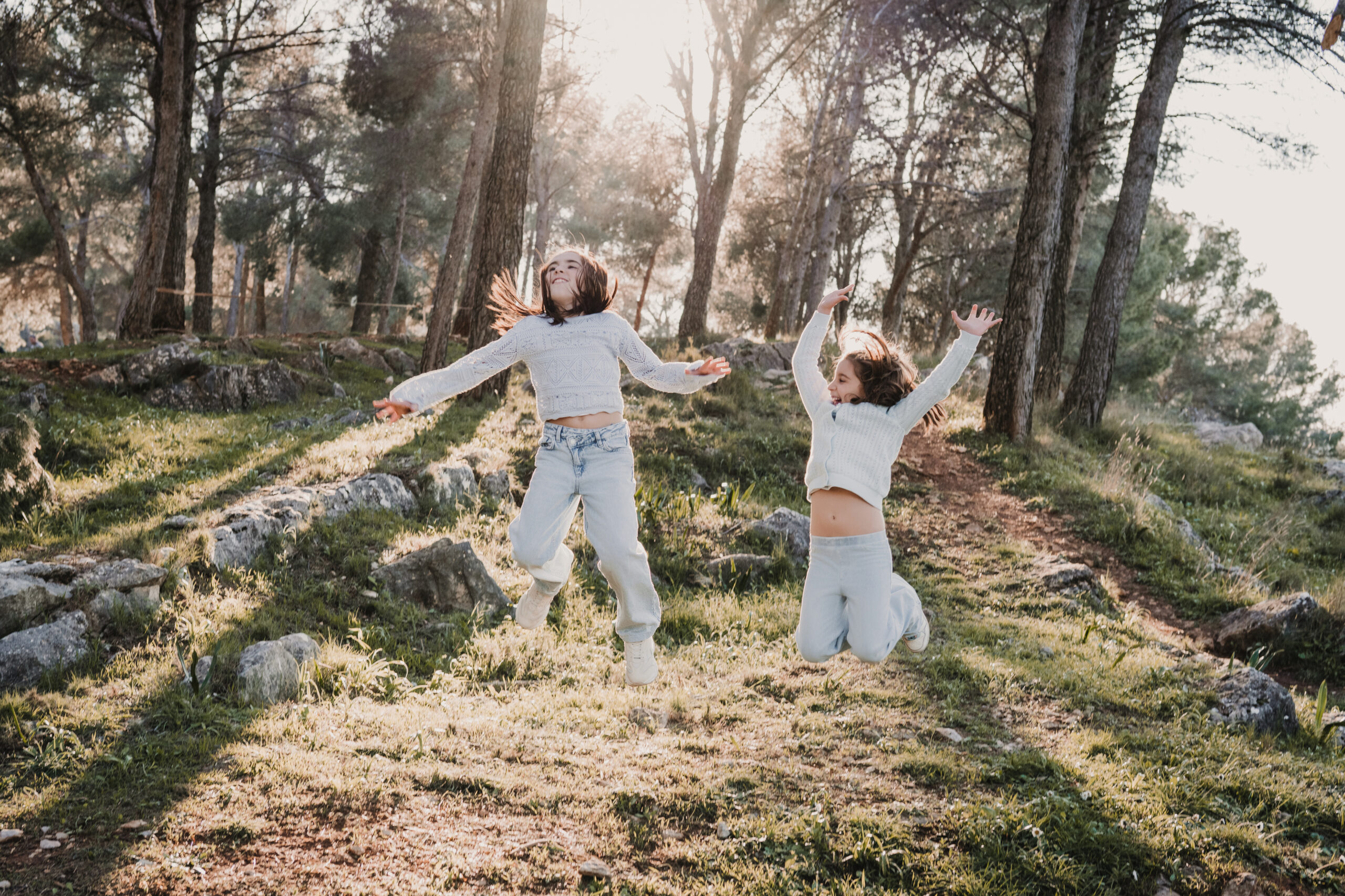 Dos hermanas saltando juntas durante una sesión de fotos de comunión en Jaén